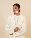 Person wearing a butter yellow abaya holding a flower against a beige background