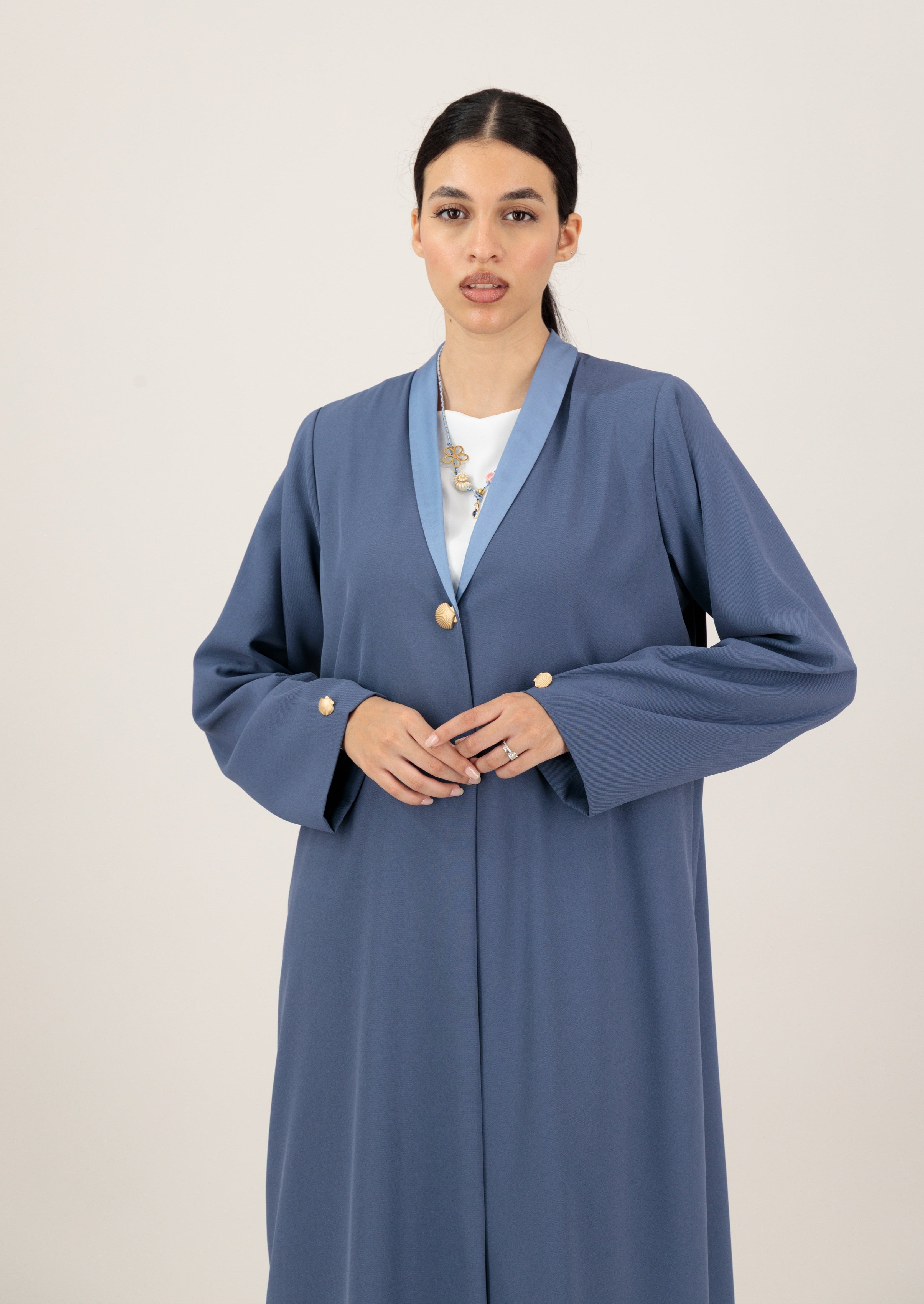 Woman wearing a long blue coat with a white background