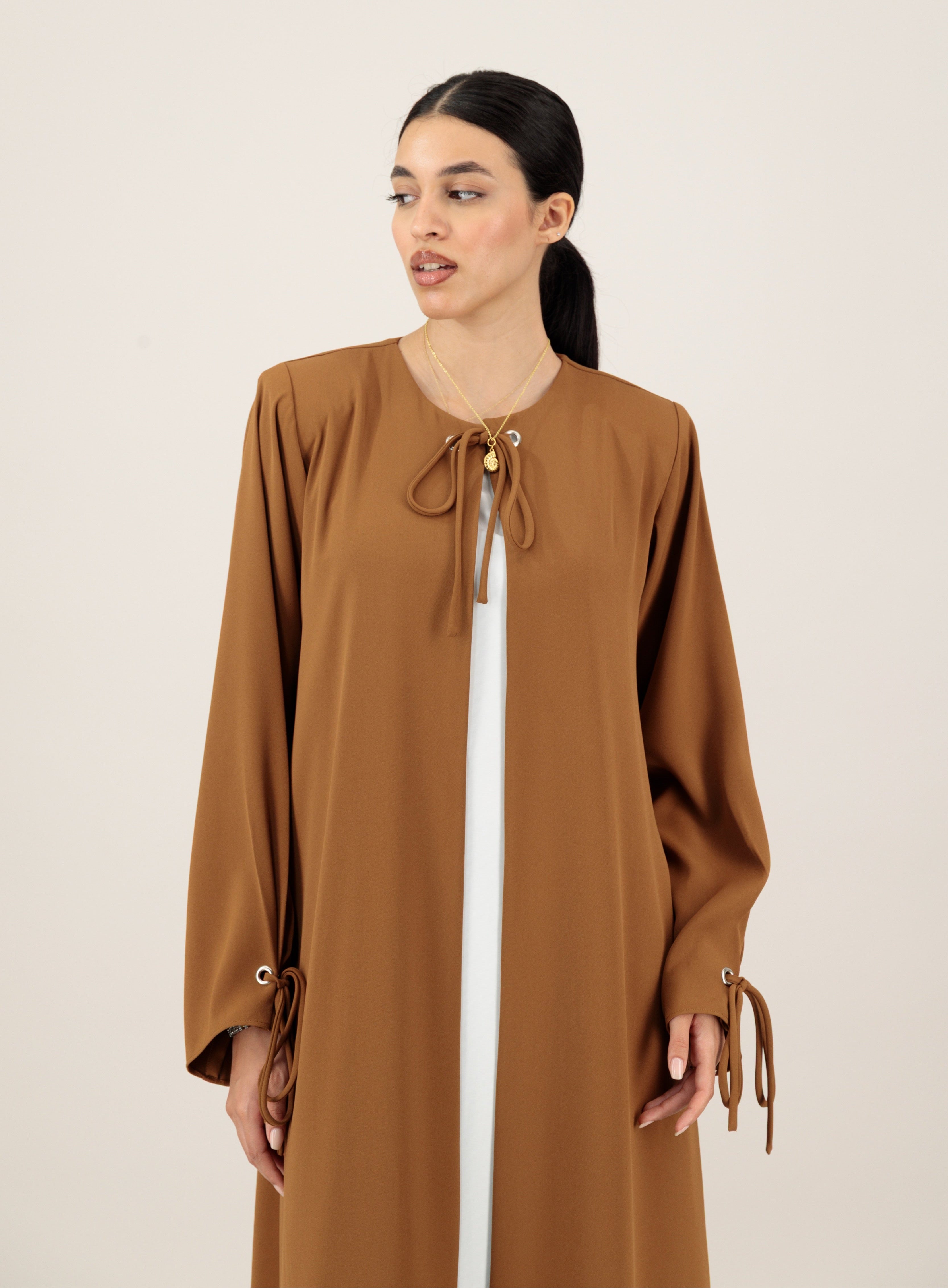 Woman wearing a brown dress with long sleeves on a beige background